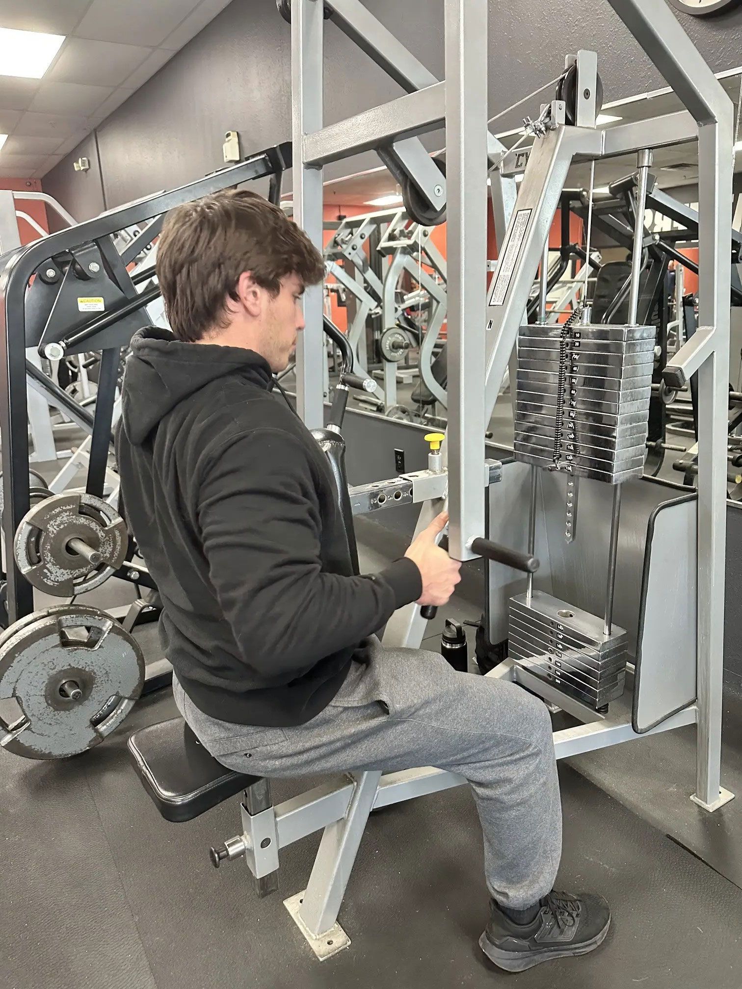 Man seated, using a cable row machine at a gym, pulling handle toward body.