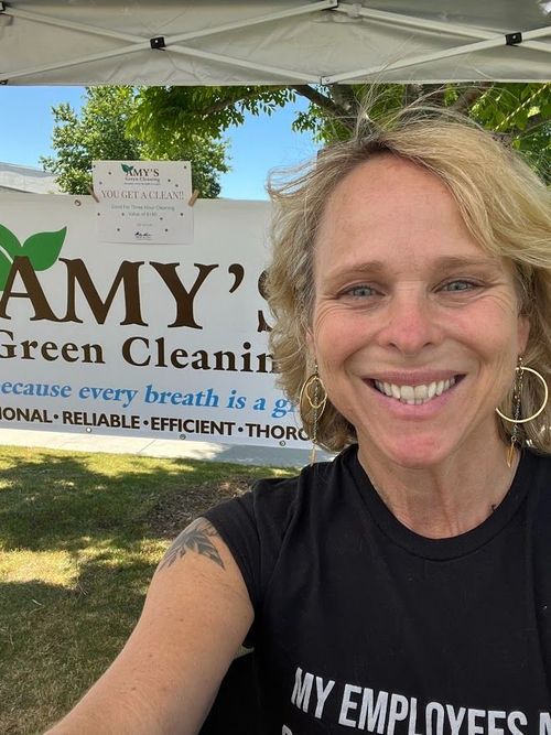 A woman is smiling in front of a sign that says amy 's green cleaning