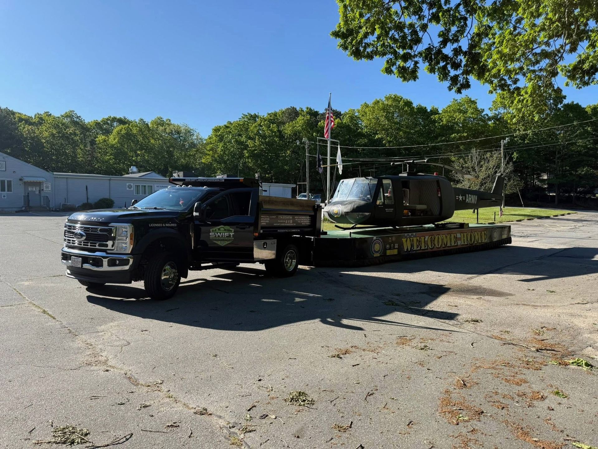Tow truck hauling a black utility vehicle on a flatbed in a sunny parking lot