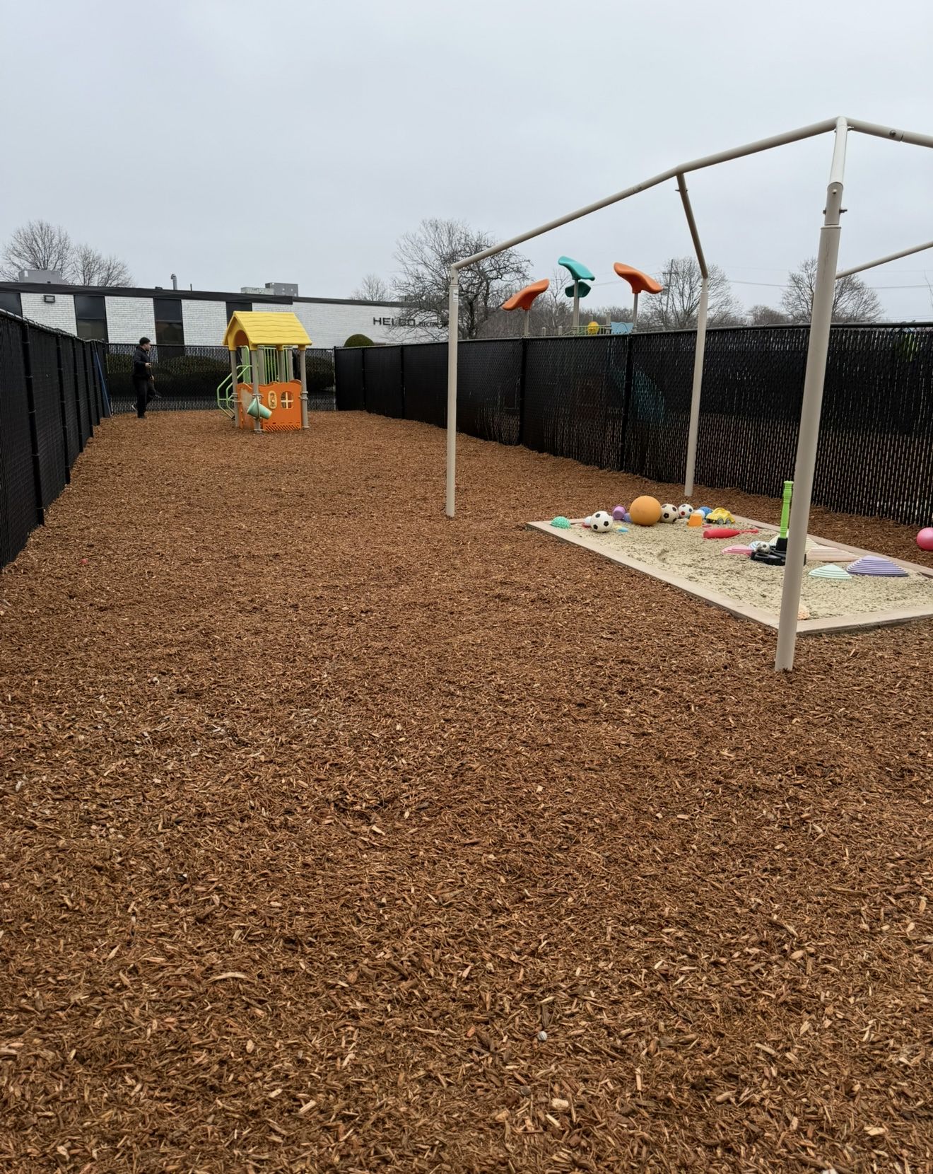 Playground with wood chips, fencing, and colorful equipment.