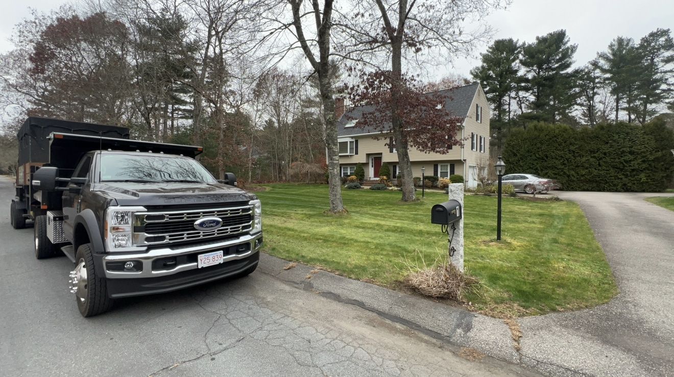 A black dump truck parked on a residential street in front of a house.