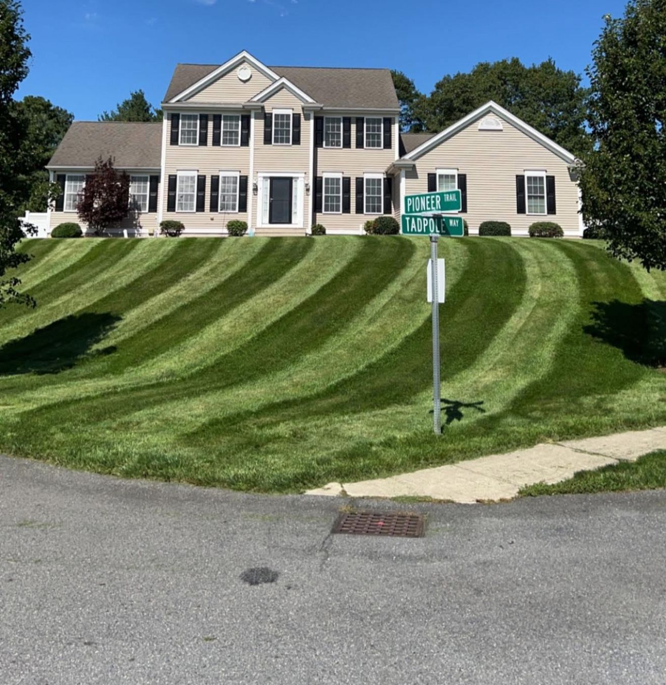 Two-story house with striped lawn; street sign reading 
