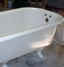 White clawfoot bathtub in a workshop, with a drain opening and faucet holes visible.