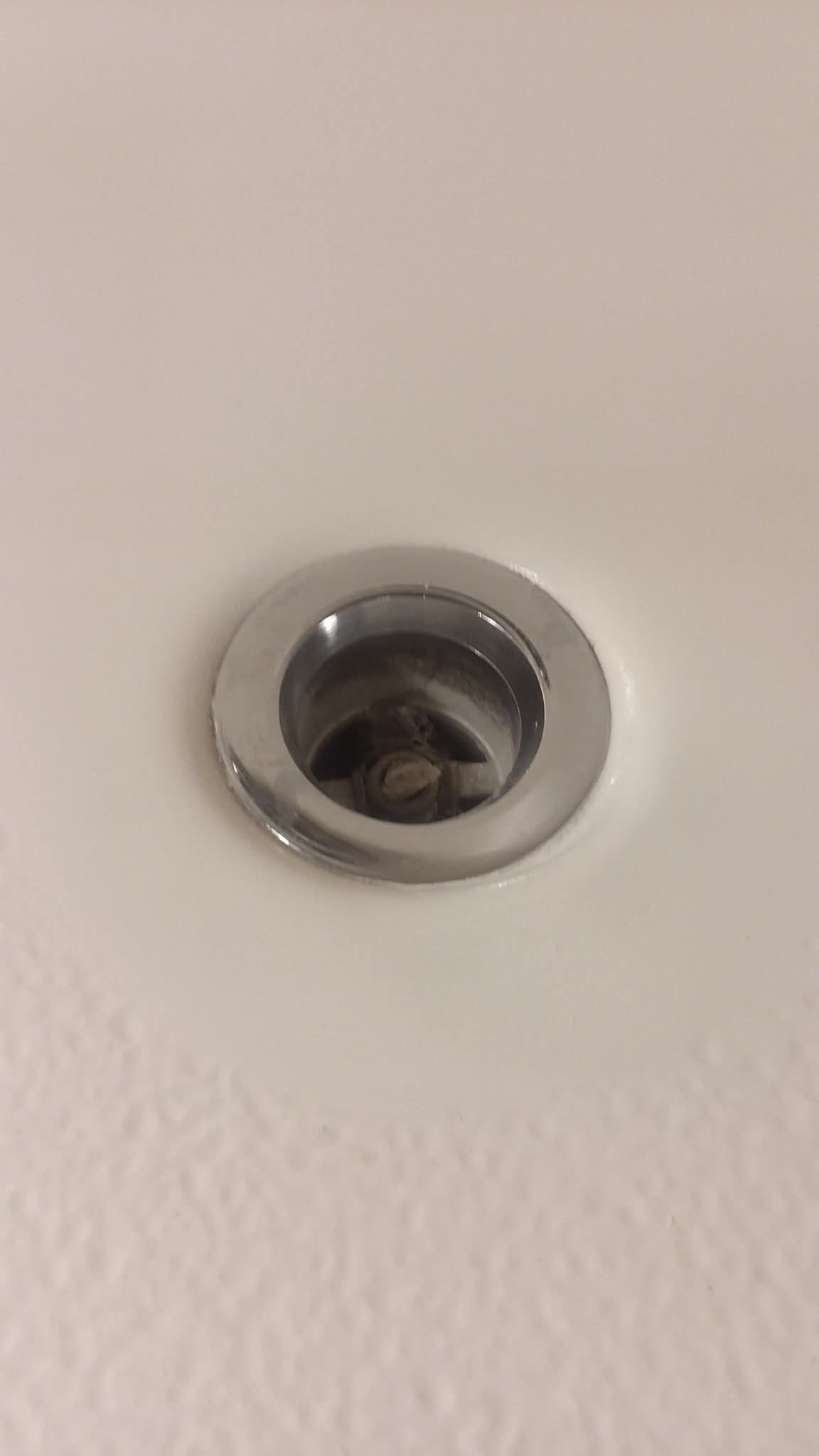 Close-up of a chrome recessed ceiling light on a beige wall.
