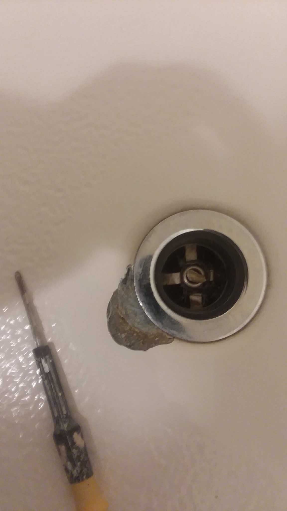 Close-up of a silver shower valve on a beige wall with a screwdriver beside it.