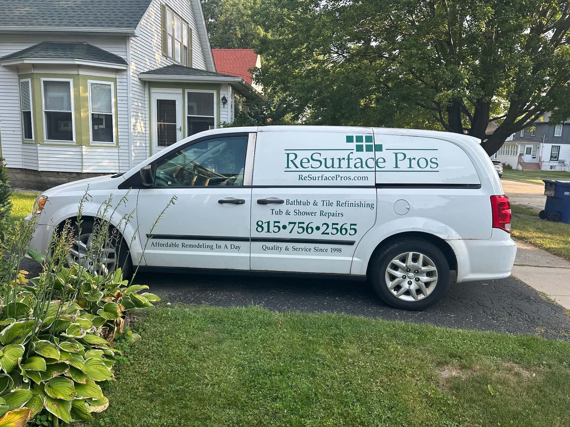 White “Resurface Pros” service van parked in front of a house on a grassy lawn