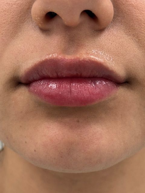 Close-up of a person's lips. The lips are full, slightly glossy, and a reddish-pink color.