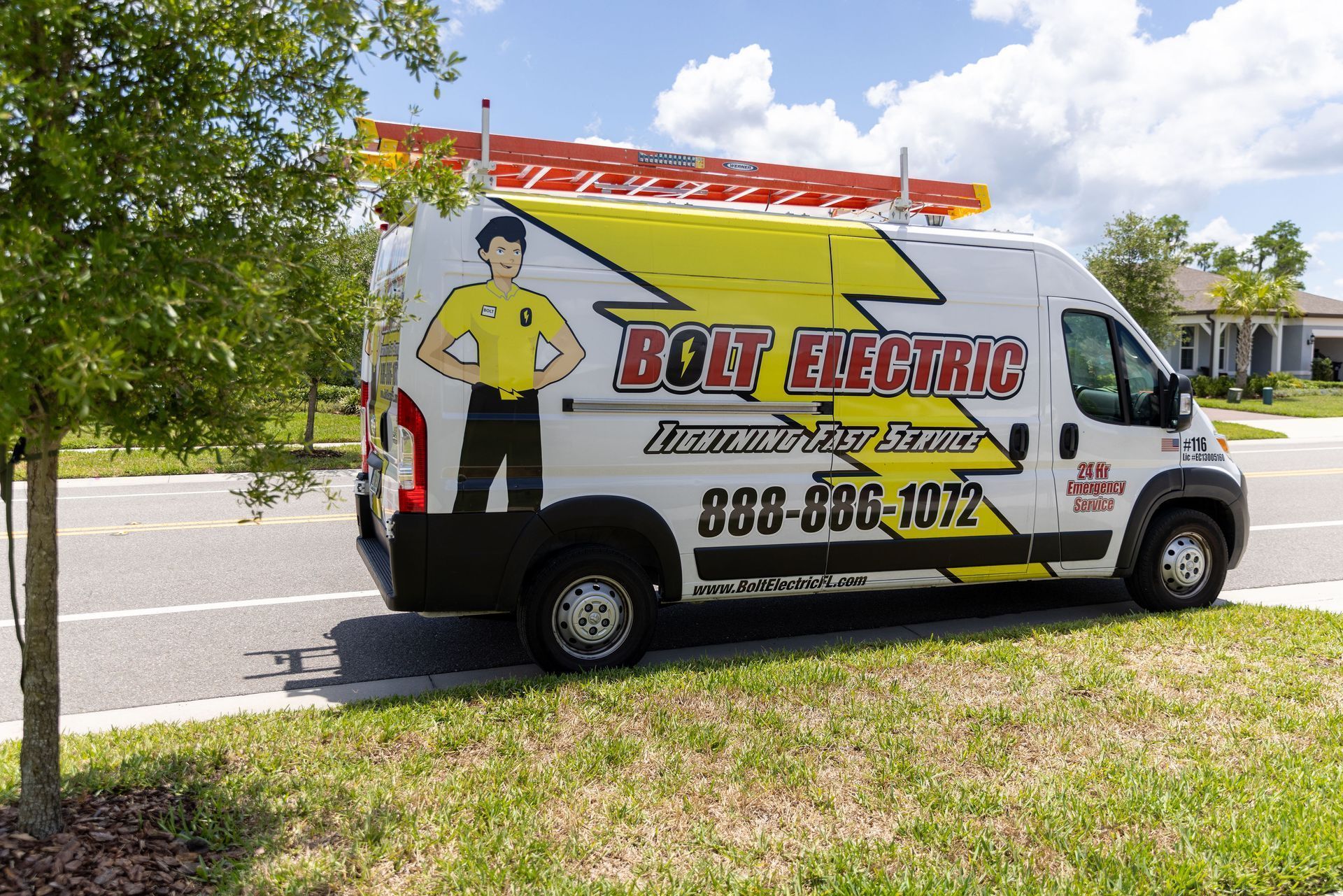 White Bolt Electric van with ladder, logo, and phone number, parked on a road with grass and a tree.