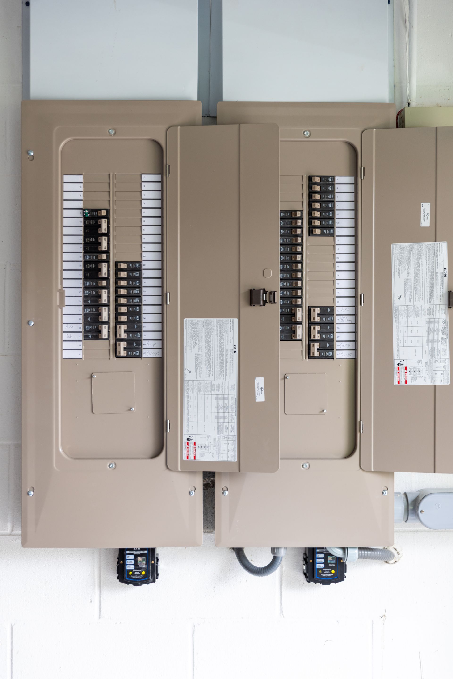 Two beige electrical breaker boxes on a white wall.