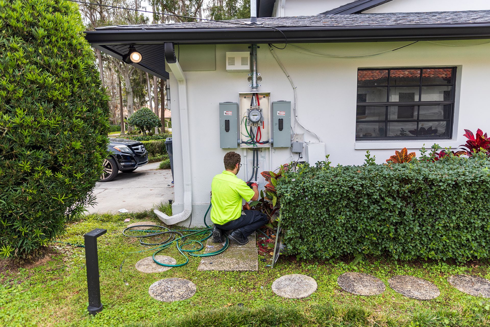 Person working on an electrical panel outside a house.