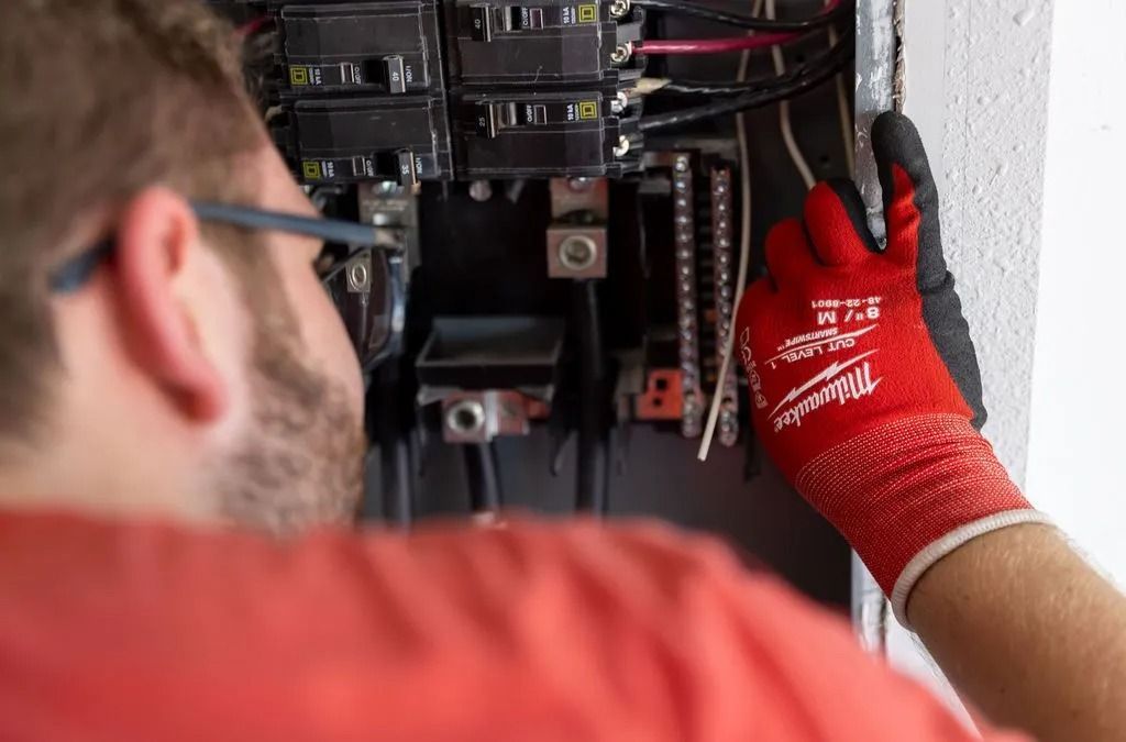 Person wearing red gloves working on an electrical panel.