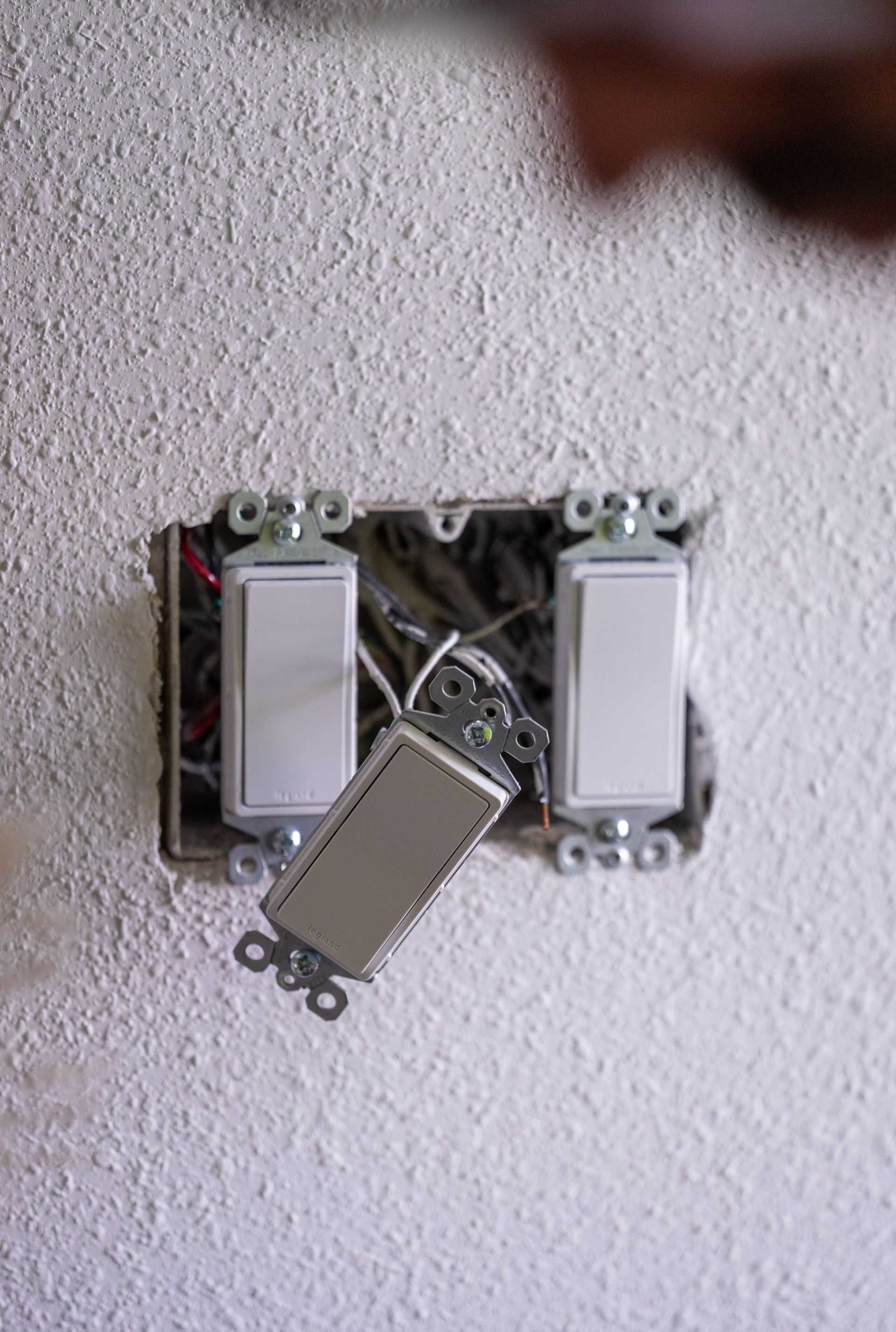 Light switches were removed from the wall. Wires are visible in the electrical box.