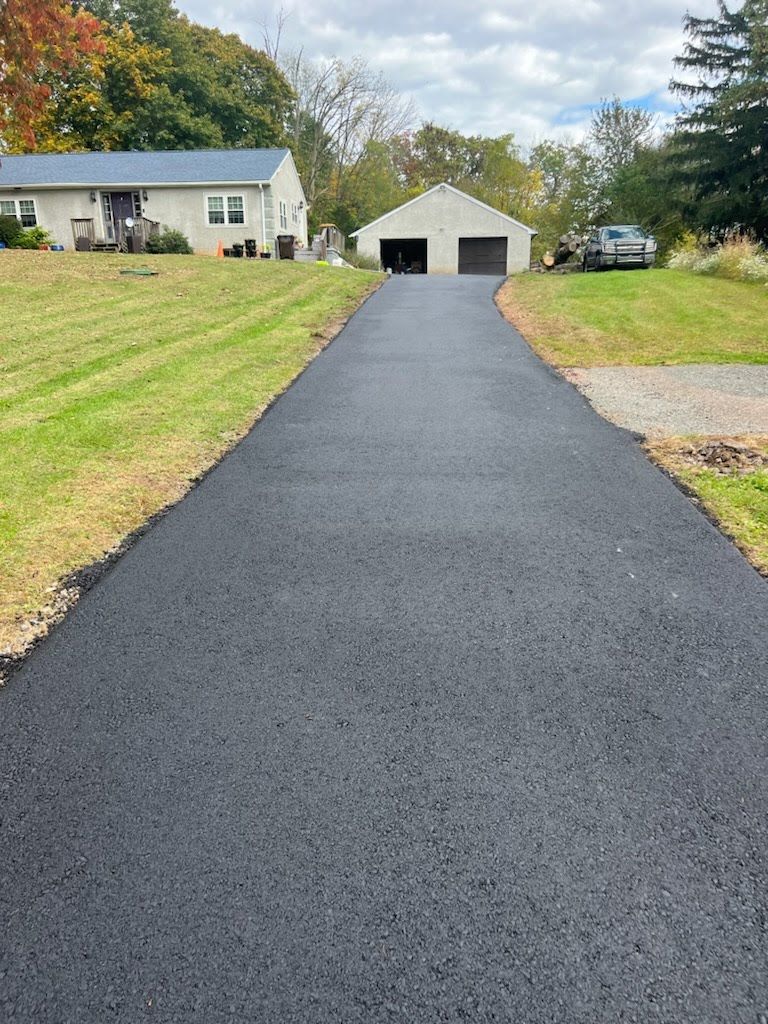 a driveway leading to a house with a garage and a house in the background .