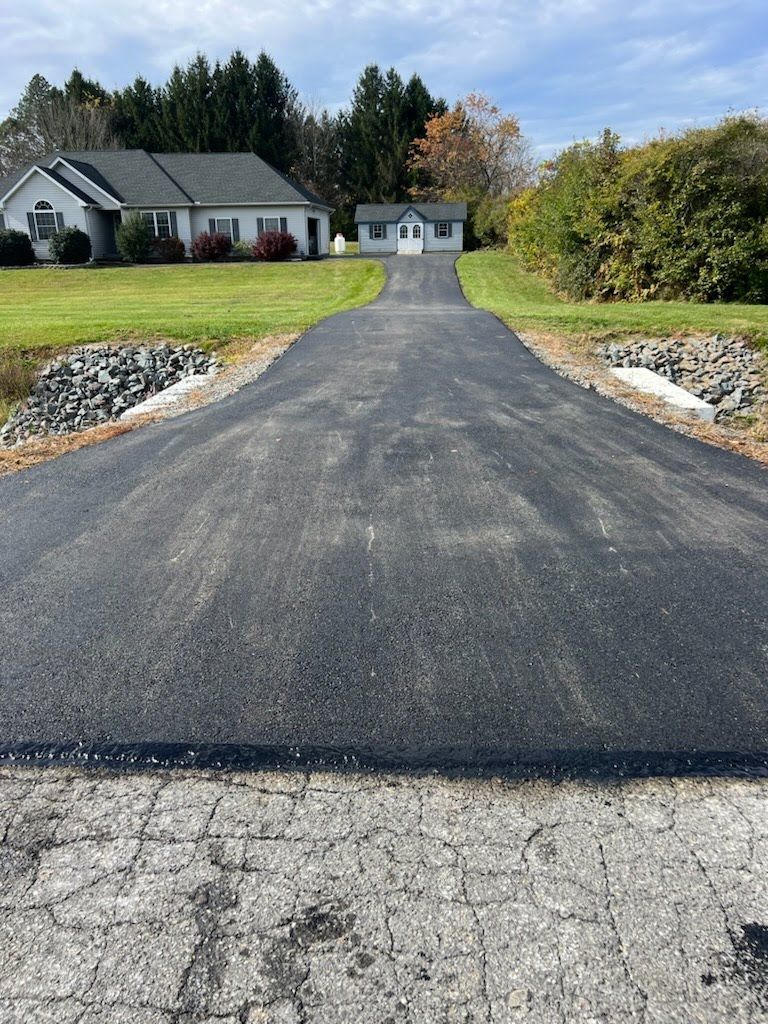 a driveway leading to a house in the middle of a field .