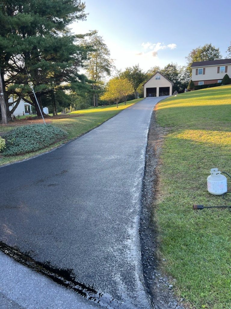a driveway leading to a house with a propane tank on the side of it .