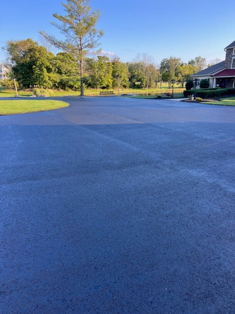a black asphalt driveway with a red house in the background
