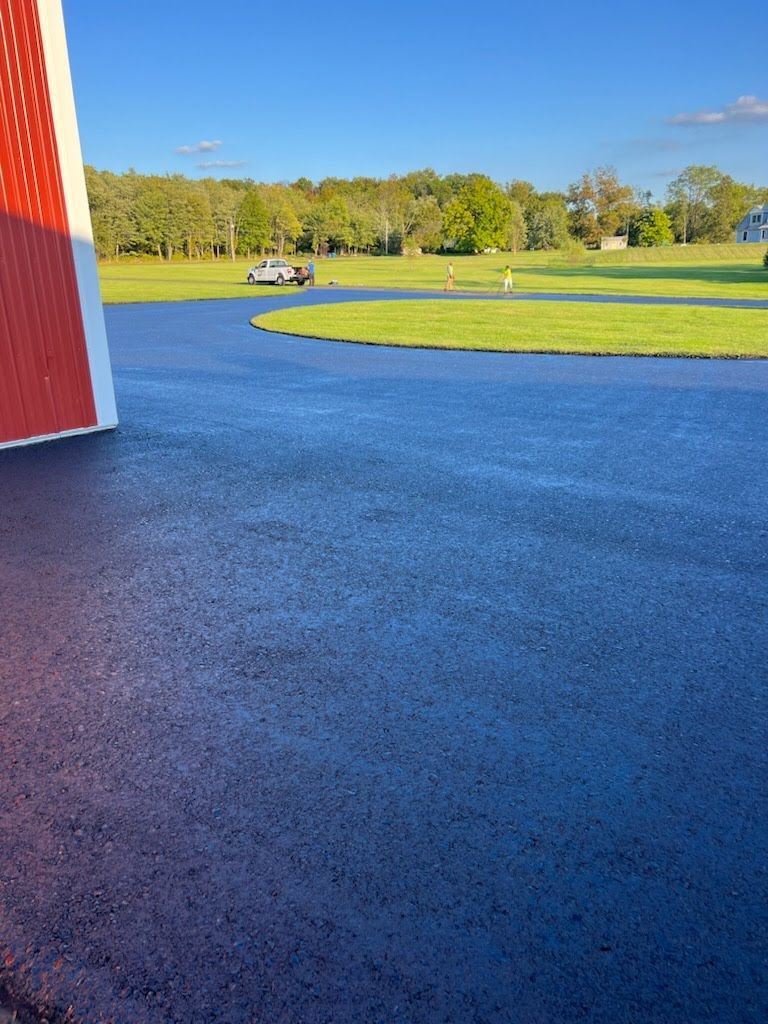 a car is parked on the side of a road next to a barn .