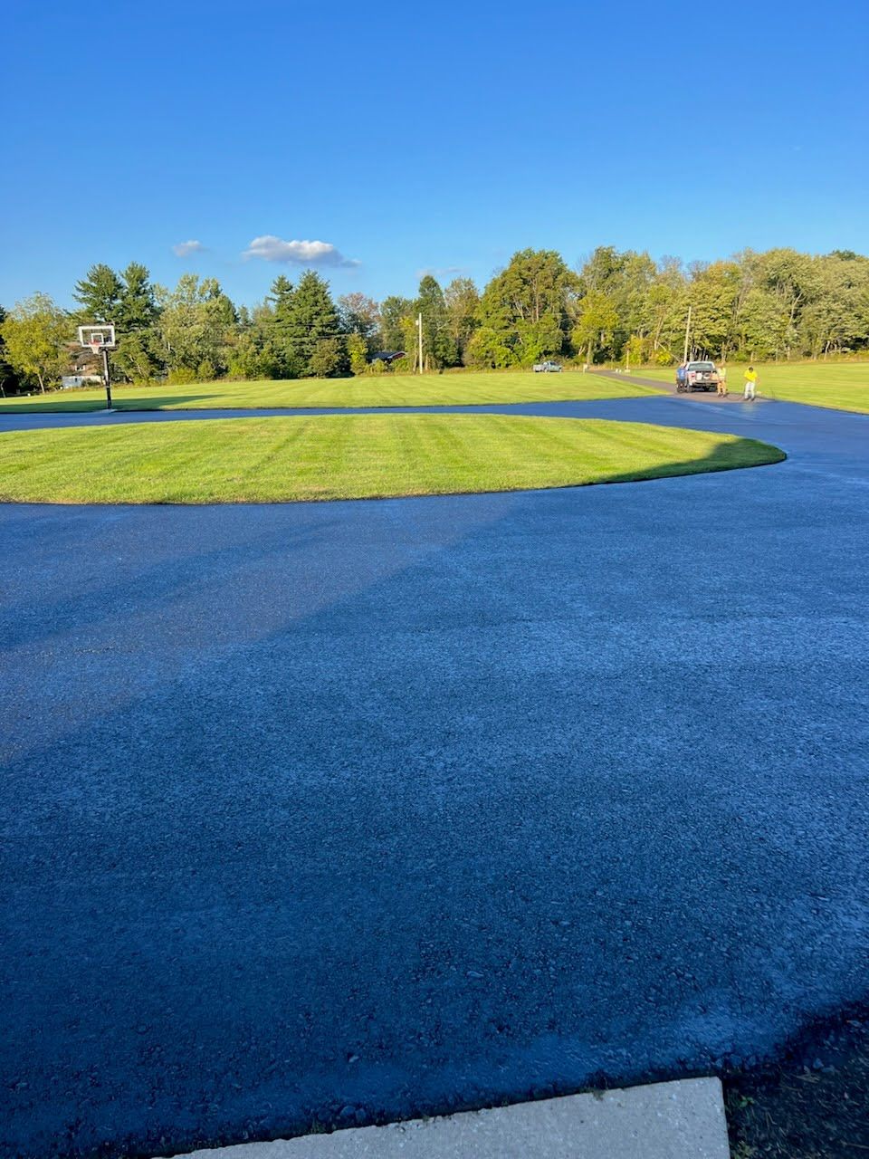 a lush green field with a blue road in the foreground