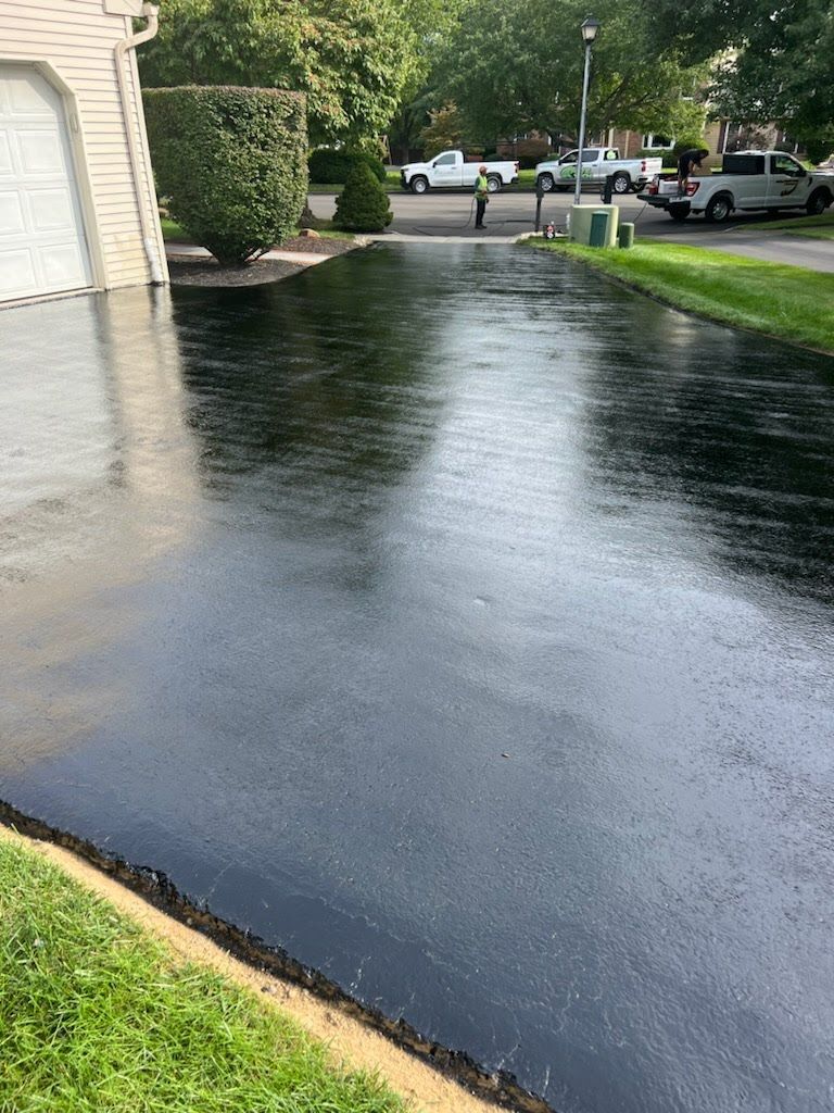 a black asphalt driveway with a white truck parked on the side of it .