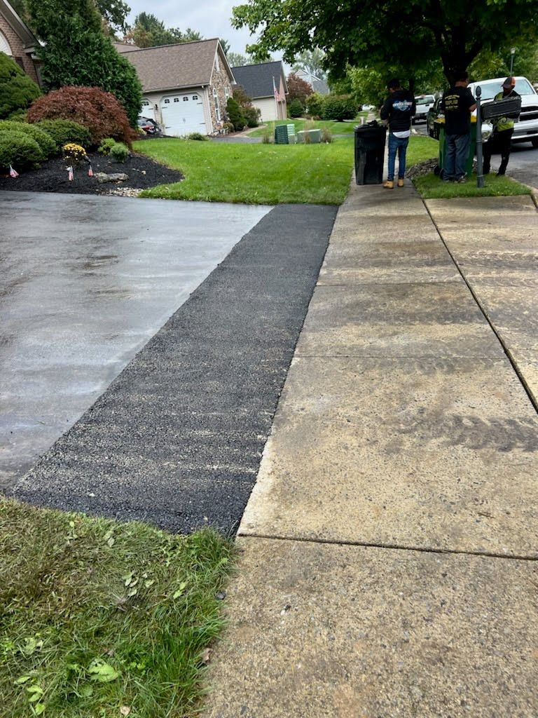 a couple of people standing on a sidewalk next to a driveway .