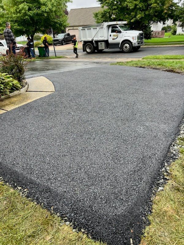 a dump truck is driving down a newly paved driveway .