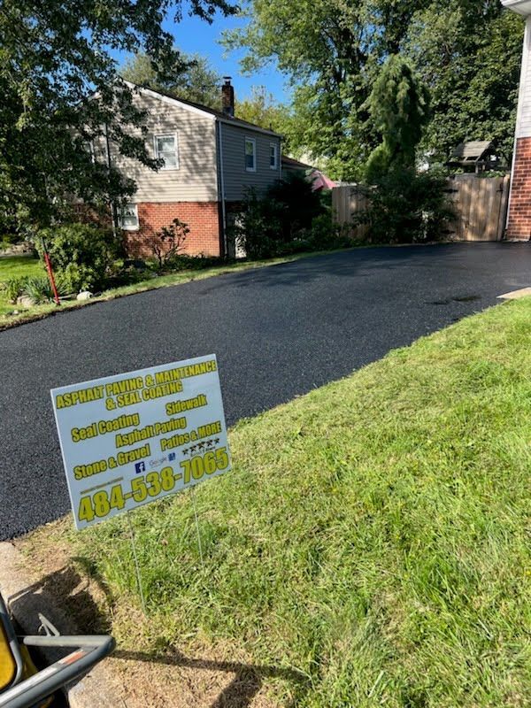 a sign is sitting on the side of a driveway next to a house .
