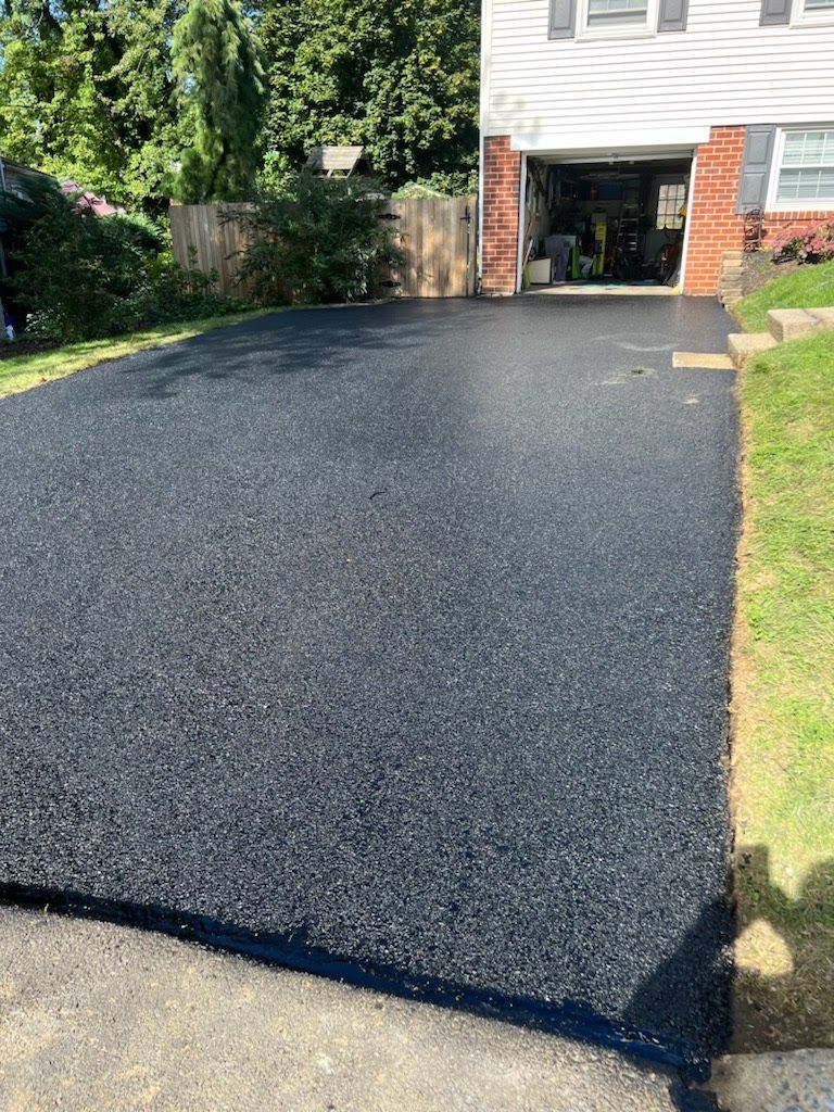 a black asphalt driveway is being installed in front of a house .