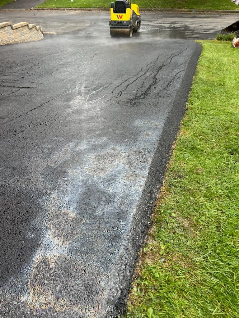 a yellow roller is rolling asphalt on a road .