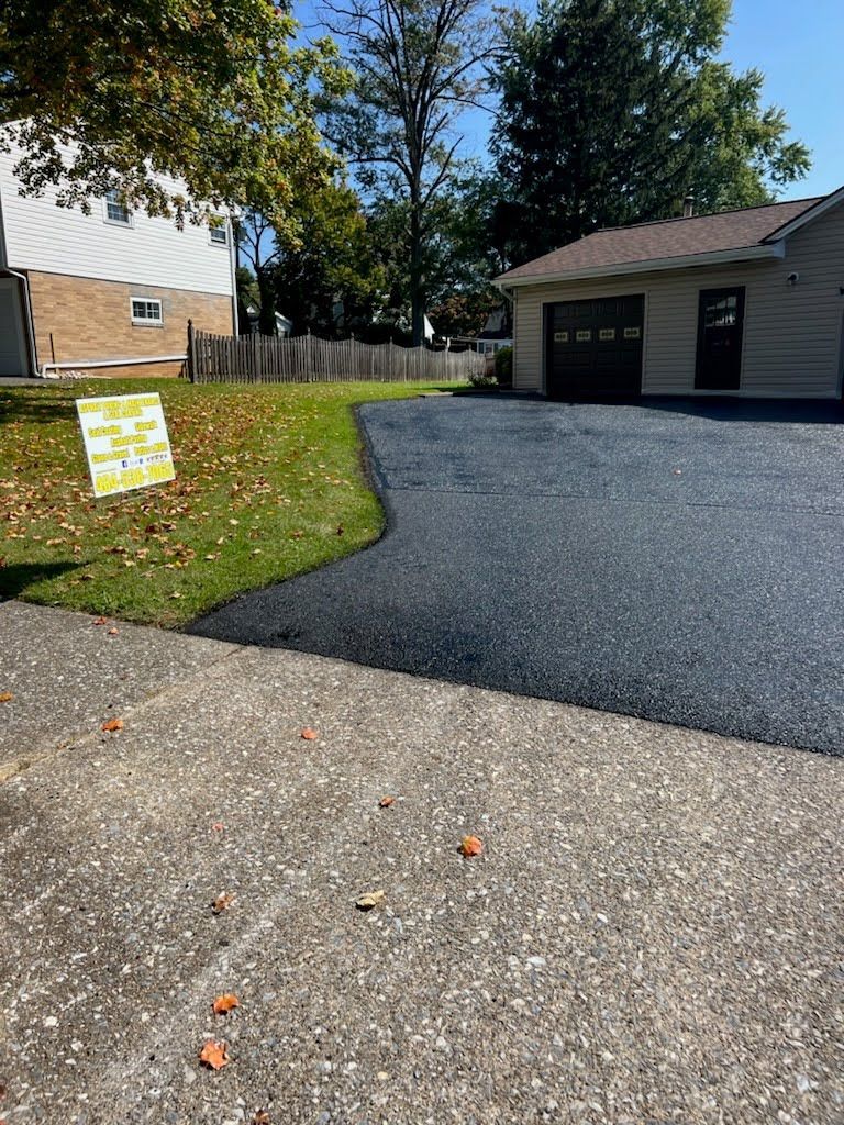 a driveway with a sign on the side of it and a house in the background .