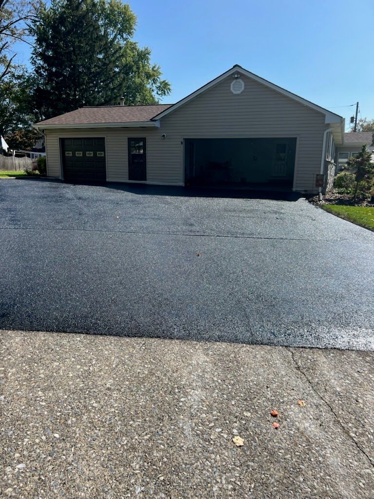 a house with a garage and a driveway that has been paved .