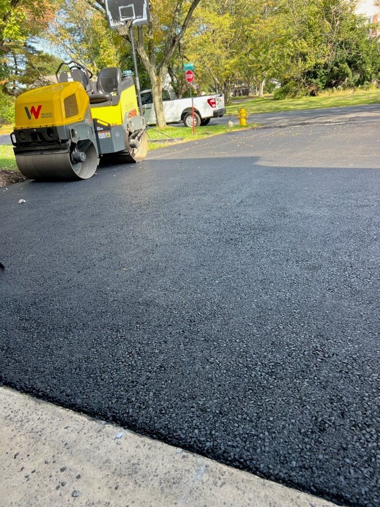 a yellow roller is sitting on top of a black asphalt road .