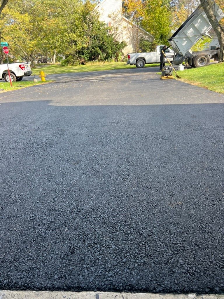 a black asphalt driveway with a white truck parked on the side of it .