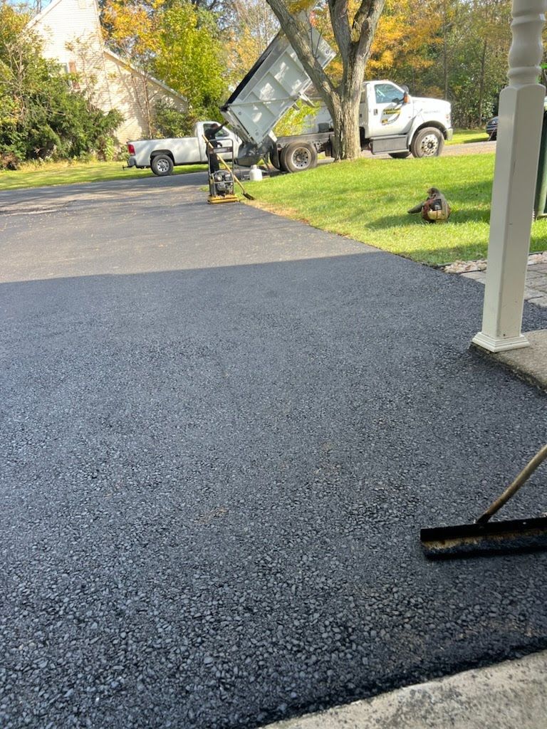 a broom is being used to spread asphalt on a driveway .