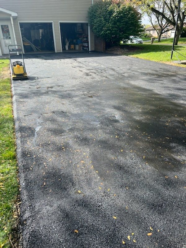 a driveway with a lawn mower in front of a house .