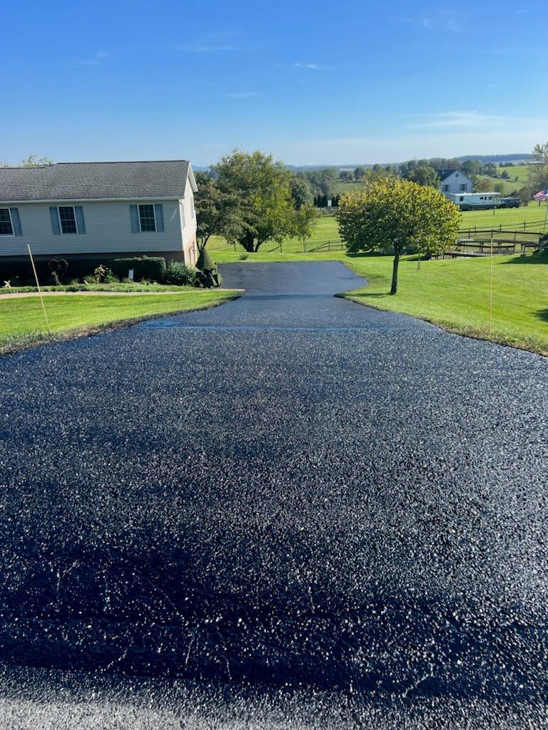 a driveway with a house in the background and trees on the side .