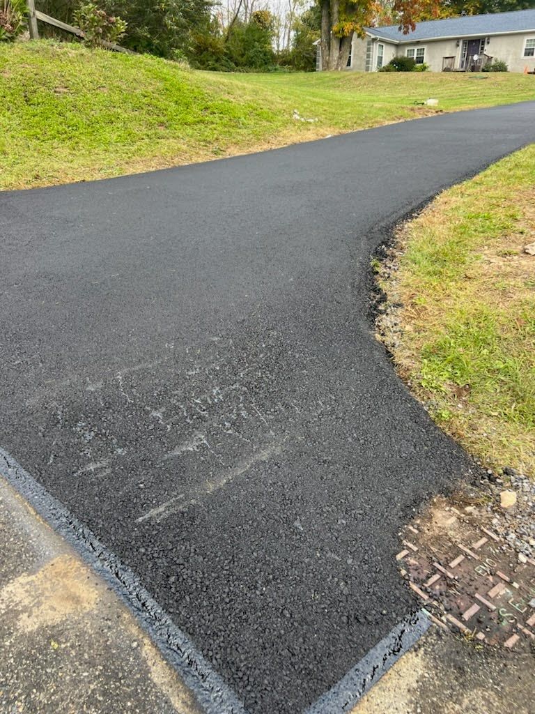a black asphalt driveway leading to a house .