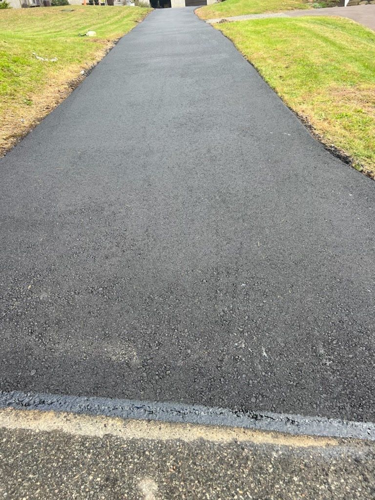 a black asphalt driveway with grass on the side of it .