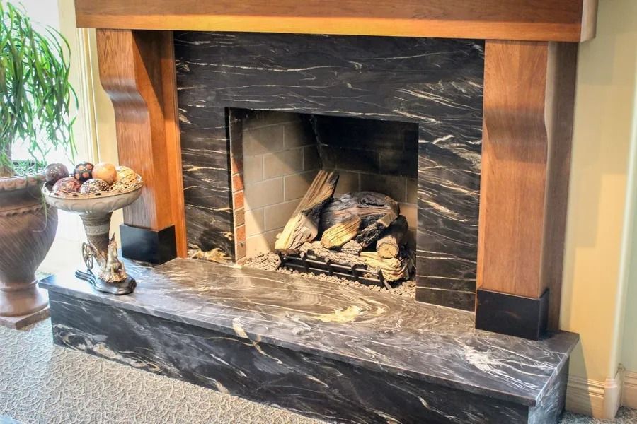Fireplace with black marble surround and wooden mantel.