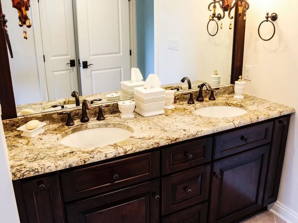 Dark wood double vanity with granite countertop and two sinks in a bathroom.