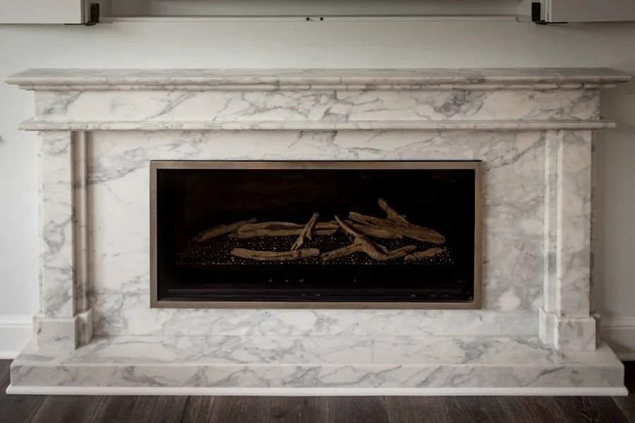 Marble fireplace with gray veining and a dark interior.