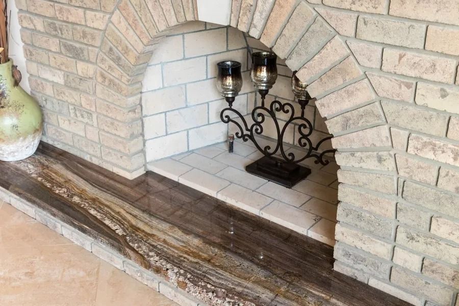 Brick fireplace with archway, adorned with candles and granite hearth.