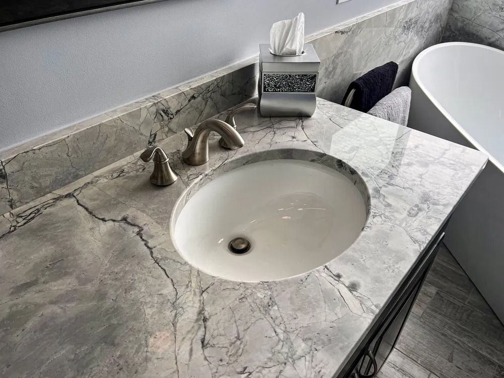 Bathroom vanity with a white oval sink, marble countertop, and chrome faucet.
