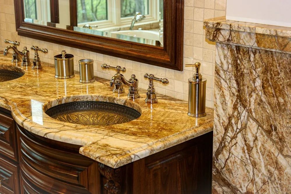 Bathroom with marble countertop, dark wood cabinets, round sinks, and ornate faucets.