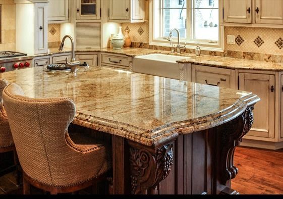 Kitchen with a granite countertop island, beige cabinets, and a farmhouse sink.