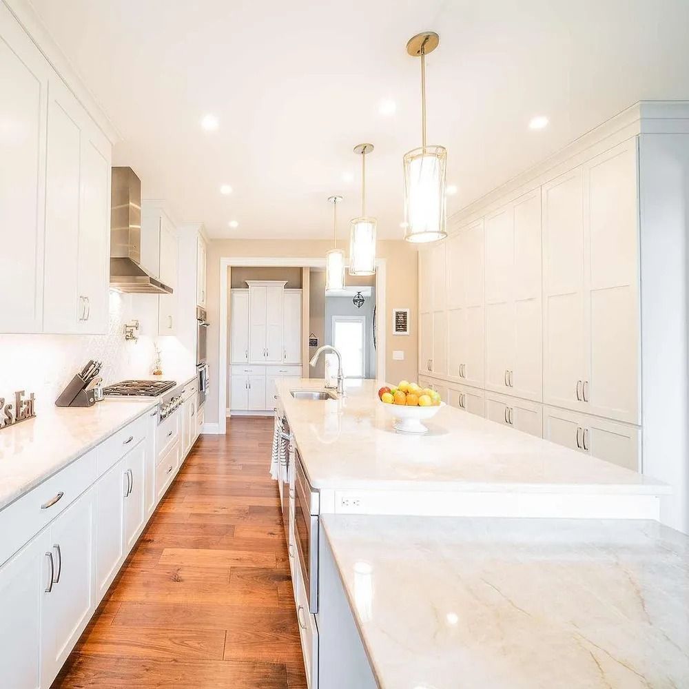 White kitchen with island, cabinets, and appliances on hardwood floors.