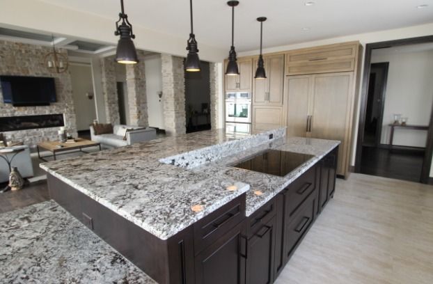 Modern kitchen with granite countertops, dark cabinets, and pendant lights.