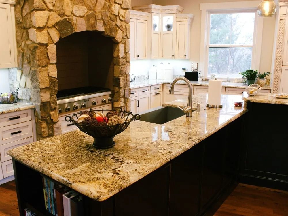 Kitchen with stone range hood, granite countertops, white cabinets, and dark island.