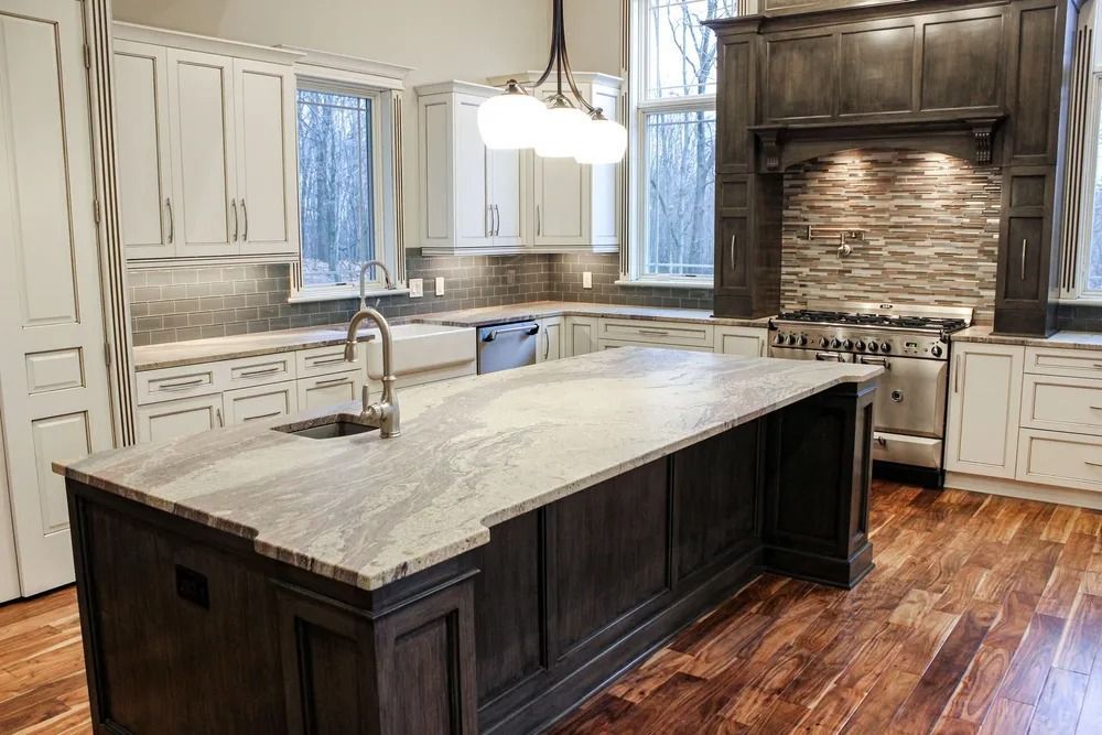 Elegant kitchen with dark wood island, light cabinets, and granite countertops.