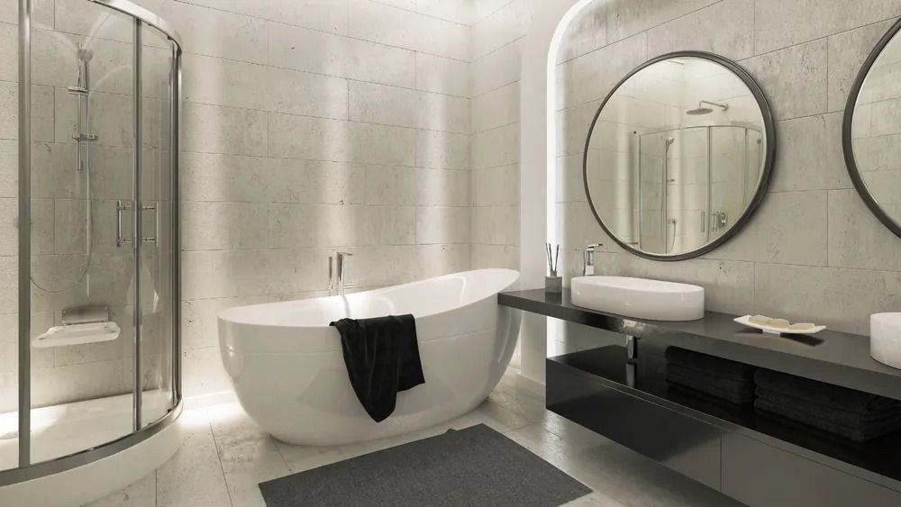 Modern bathroom with a white bathtub, glass shower, and round mirrors.