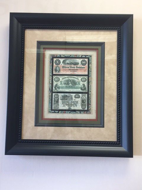 A framed picture of money is hanging on a wall.
